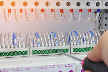 Installation of electrical wiring wires with a screwdriver in the electrical control panel. 