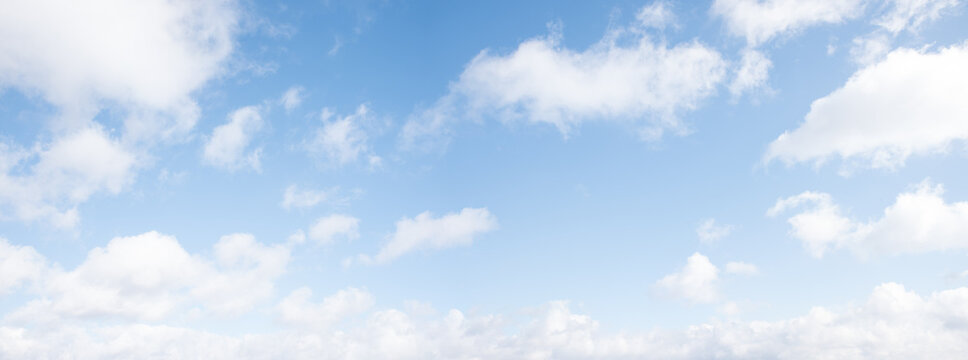 light blue sky background with fluffy fair weather clouds, panorama format