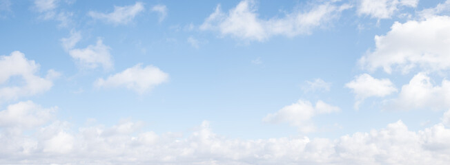 light blue sky background with fluffy fair weather clouds, panorama format