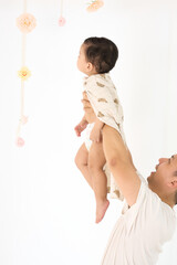 An 18-month-old Asian boy wrapped in a bath towel, walking with a superhero pose