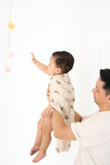 An 18-month-old Asian boy wrapped in a bath towel, standing with a superhero pose