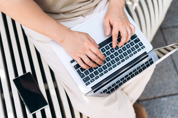 Freelancer working on laptop outdoors with smartphone nearby