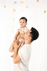 An 18-month-old Asian boy wrapped in a bath towel, standing with a superhero pose
