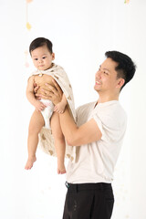 An 18-month-old Asian boy wrapped in a bath towel, walking with a superhero pose