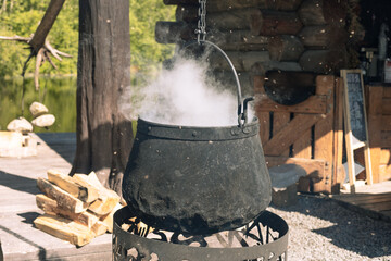 cooking food over an open fire in a pot, Cauldron over bonfire shrouded in smoke. Cooking food...