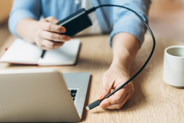 Businessman connecting power bank to laptop at desk