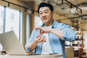 Asian freelancer gesturing during video call in coworking space
