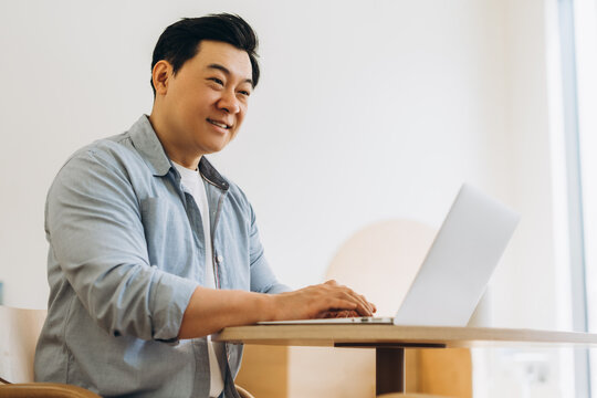 Asian freelancer working remotely from home office using laptop - Powered by Adobe