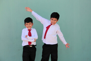 Two dark-skinned Latino male classmates dressed in uniform are excited and happy to be back in school