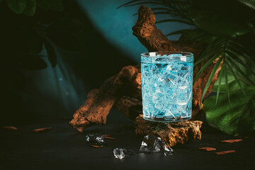 Blue alcoholic cocktail drink with vodka, blue curacao liqueur, soda, ice and lemon. Dark...