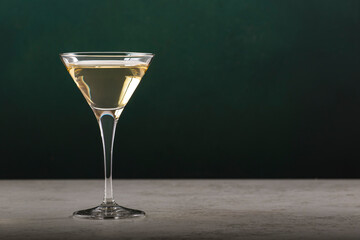 Italian white vermouth alcoholic drink in glass on dark green background