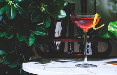 Killer Queen alcoholic cocktail drink with gin, aperitif, bitters, liqueur and lemon twist with bar...