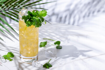 Yellow alcoholic cocktail drink with tequila, agave syrup, cilantro, jalapeno, lime juice and soda