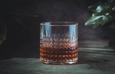 Smoky whiskey, bourbon or scotch in glass. Dusk green background, elegant night decoration
