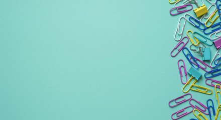 Colorful paperclips arrangement on teal background