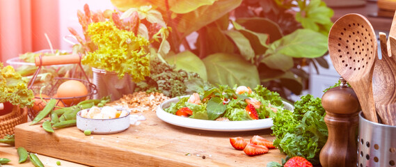 Fresh salad with lettuce and shrimps in cozy modern kitchen on wooden table