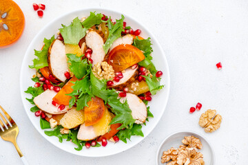Autumn persimmon salad with grilled chicken fillet, pomegranate seeds, walnuts, oranges and...