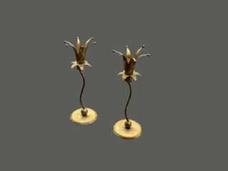 The grey-black background of the image is a gold-colored metal candle holder decorated with a gold...