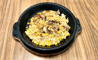 A sizzling hot iron plate of food with pepper rice and meat mixed with soy sauce