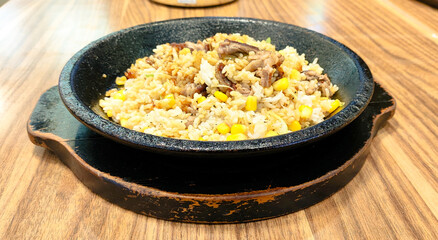 A sizzling hot iron plate of food with pepper rice and meat mixed with soy sauce