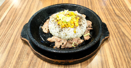 A sizzling hot iron plate of food with pepper rice and meat mixed with soy sauce