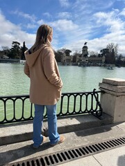 Reflection by the Lakeside: A woman gazes out across a serene lake, taking in the architectural...