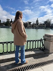 Serene Reflection by the Lake: A solitary figure gazes out over a tranquil lake, the water...