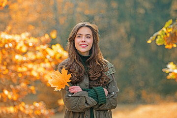 Autumn woman portrait in autumn fall. Woman with fall leaves. Romantic portrait in autumn foliage. Model on autumn nature. Woman with falling leaves.