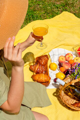 Outdoor picnic with pastries, fruit, and wine in a sunny meadow. Fresh fruit, croissants, and a...