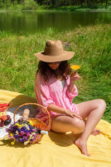 Woman enjoying a picnic outdoors with food and flowers in the sun. She enjoys a refreshing drink...