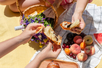 Two people are sharing a piece of bread in a relaxed picnic setting. This captures a sense of...