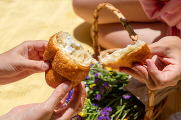 Two people are sharing a piece of bread in a relaxed picnic setting. This captures a sense of...
