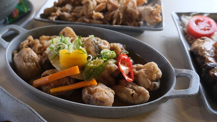 Close-up of a savory mushroom dish garnished with colorful vegetables and herbs, served in a rustic oval pan.
