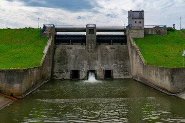 Mietków water dam in Lower Silesia, concrete structure with water flow, green embankments,...