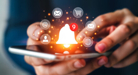 Closeup of a person holding a smartphone with a glowing notification bell icon surrounded by various app icons, symbolizing digital communication and alerts