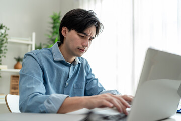Depressed Asian man freelancer using laptop device working in house. 