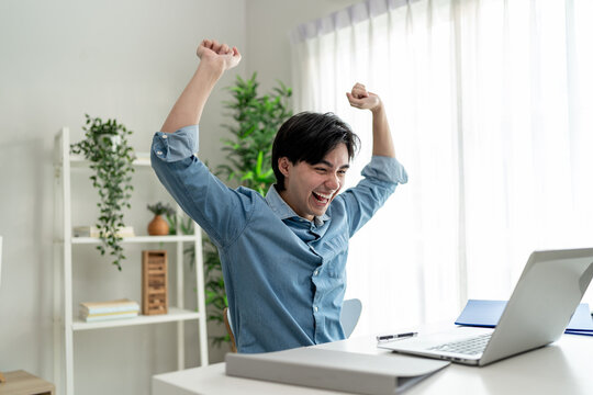 Asian excited man freelancer using laptop device working in house.