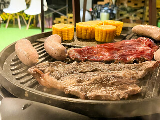 ジュージューと焼かれる肉とソーセージのバーベキューアップ写真