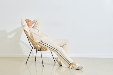 Relaxing in a modern chair, a woman enjoys a quiet moment in a minimalist indoor space
