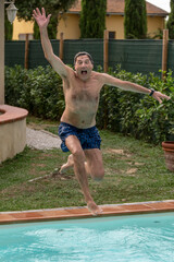 A man dives into the pool in a very awkward and funny way