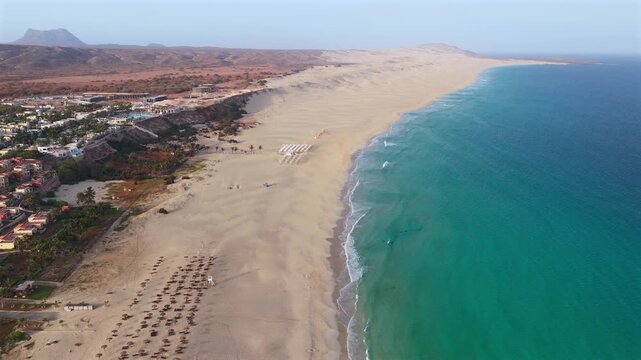 Aerial view of Chaves beach (Praia de Chaves) parasol,sandy beach, famous resort and background a volcanic mountain.Boa Vista island in the Atlantic Ocean.Cape Verde, Africa.