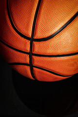 A close-up shot of a basketball against a black background highlights the texture and design. Focus...