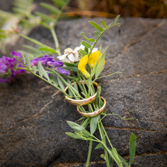 Wedding rings in flowers on a rock
