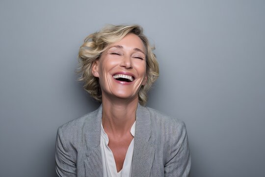 Businesswoman giggling in studio portrait against gray background  
