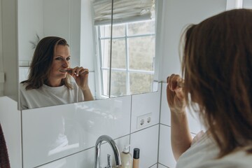 Woman brushing teeth in bright bathroom. Morning routine, dental care, hygiene, freshness, health,...
