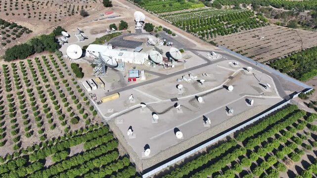 Aerial footage of a large-scale satellite ground station complex, with a multitude of dishes