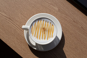 Cup of tasty caramel macchiato on wooden table