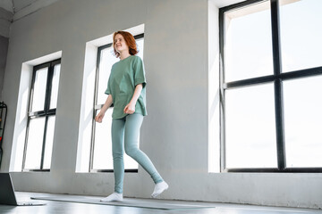 Woman practicing mindfulness and movement in a bright indoor space with large windows