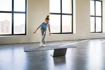Child practicing gymnastics at home in a bright room with large windows