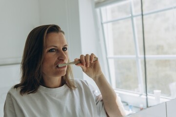 Woman brushing teeth in bright bathroom. Morning routine, dental care, hygiene, freshness, health,...